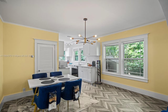 dining space with light parquet flooring, crown molding, sink, and a notable chandelier