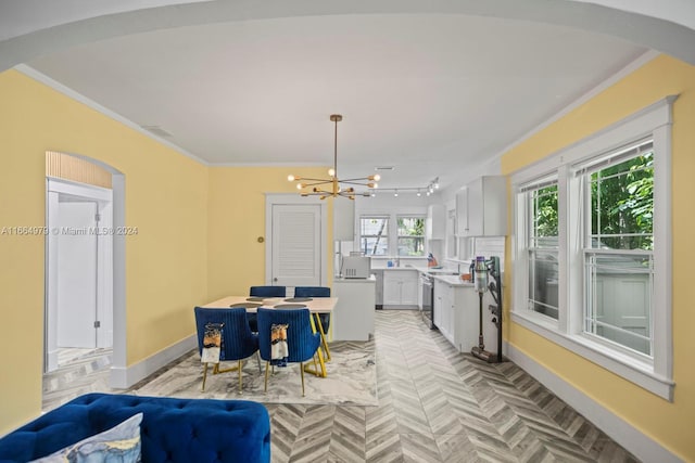 dining room with crown molding, a chandelier, and light parquet flooring