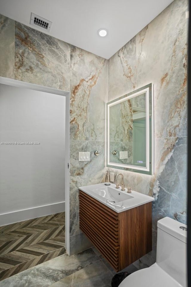 bathroom featuring parquet floors, vanity, and toilet