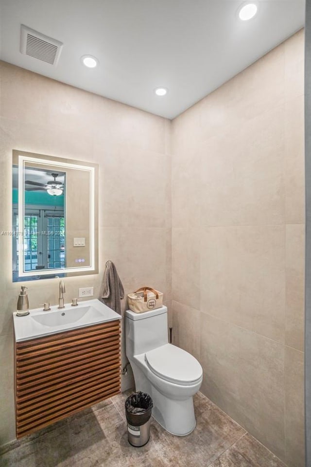 bathroom with tile walls, tile patterned floors, vanity, and toilet