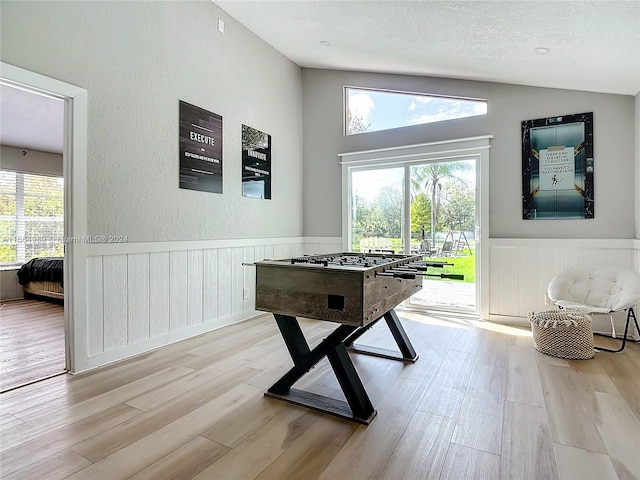 playroom with a wealth of natural light, lofted ceiling, and light hardwood / wood-style floors