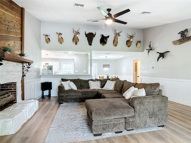 living room with wood-type flooring, a fireplace, and ceiling fan