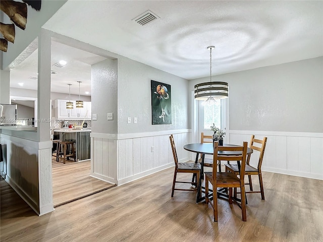 dining area with an inviting chandelier, light wood-type flooring, and a textured ceiling