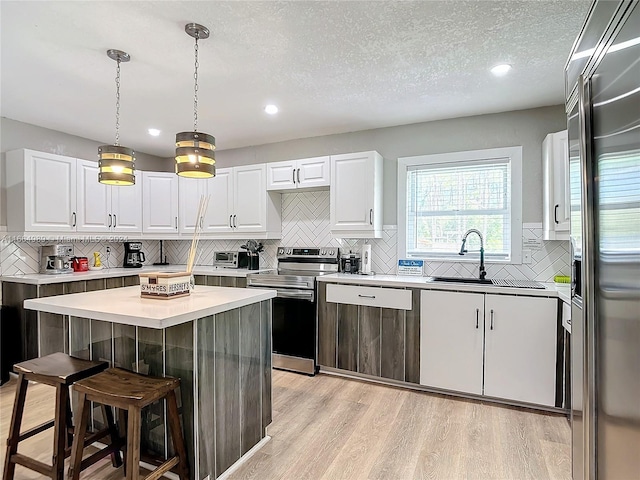 kitchen with white cabinetry, appliances with stainless steel finishes, a center island, light wood-type flooring, and a kitchen bar