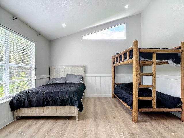 bedroom featuring a textured ceiling, light wood-type flooring, and vaulted ceiling