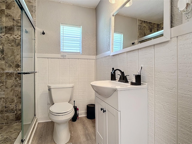 bathroom featuring wood-type flooring, vanity, toilet, and an enclosed shower