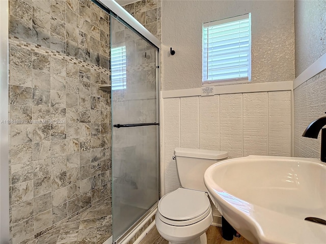 bathroom with sink, tile walls, toilet, and an enclosed shower