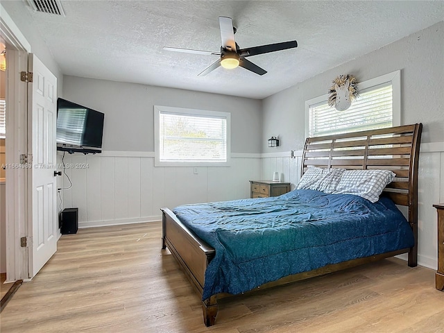 bedroom featuring ceiling fan, a textured ceiling, and light wood-type flooring