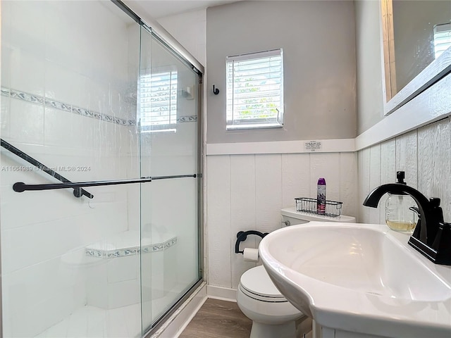 bathroom featuring toilet, wooden walls, hardwood / wood-style floors, sink, and a shower with door