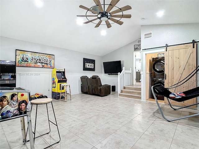 tiled living room featuring vaulted ceiling, ceiling fan, stacked washer / dryer, and a barn door