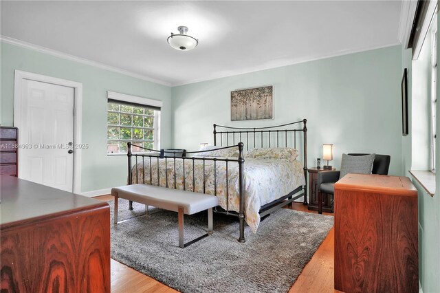 bedroom with ornamental molding and light hardwood / wood-style floors