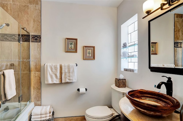 full bathroom with enclosed tub / shower combo, vanity, and toilet