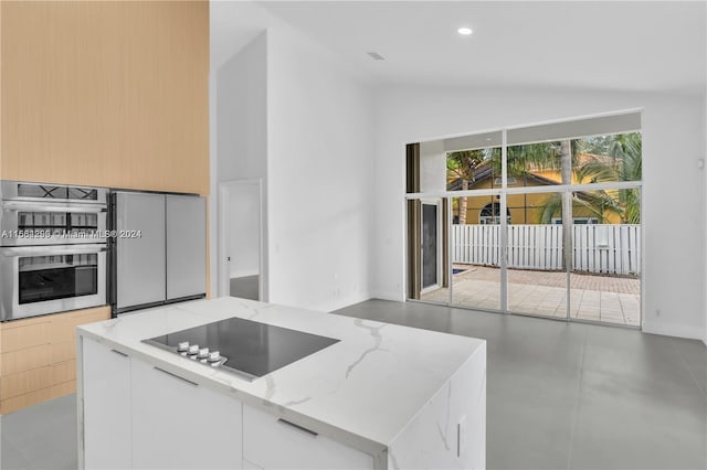 kitchen featuring light stone counters, white cabinets, lofted ceiling, black electric cooktop, and double oven