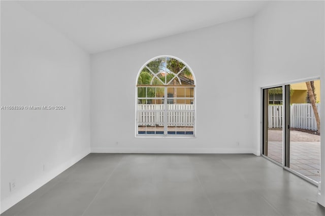 spare room with vaulted ceiling and concrete flooring