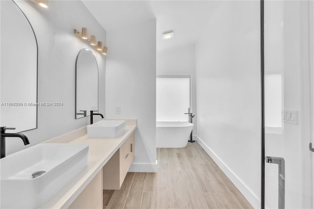 bathroom with lofted ceiling, vanity, hardwood / wood-style floors, and a bathtub