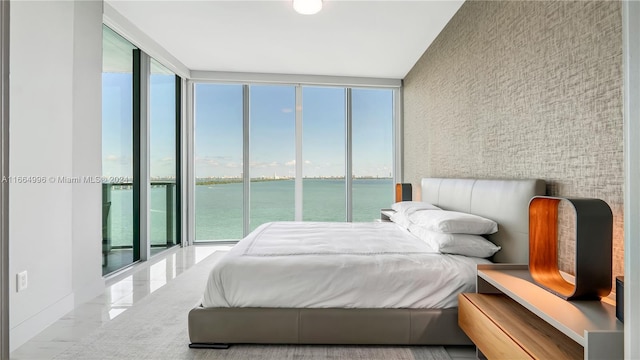 bedroom featuring a water view, a wall of windows, and access to exterior