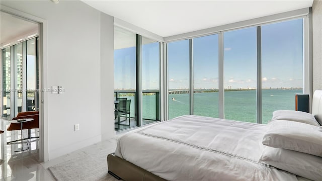 bedroom featuring access to outside, multiple windows, and a water view