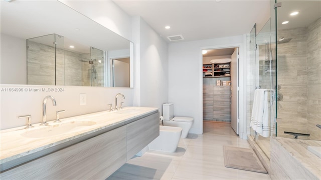 bathroom featuring vanity, tile patterned flooring, a shower with door, toilet, and a bidet