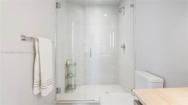 bathroom featuring vanity, a shower with shower door, and toilet