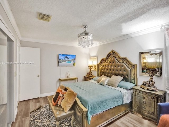 bedroom with a notable chandelier, a textured ceiling, hardwood / wood-style floors, and crown molding