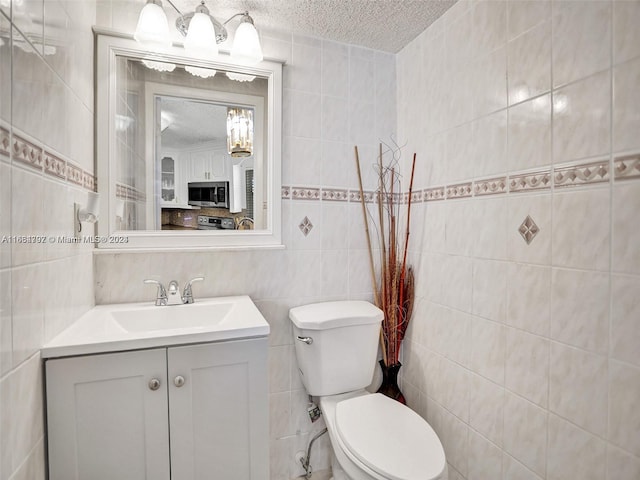 bathroom featuring tile walls, a textured ceiling, vanity, and toilet