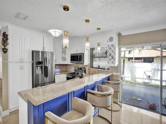 kitchen featuring stainless steel appliances, white cabinetry, a kitchen bar, and hanging light fixtures