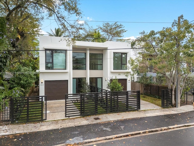 modern home featuring a garage, a fenced front yard, and stucco siding