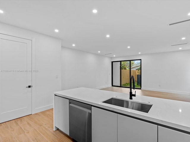 kitchen with open floor plan, stainless steel dishwasher, a sink, and white cabinetry