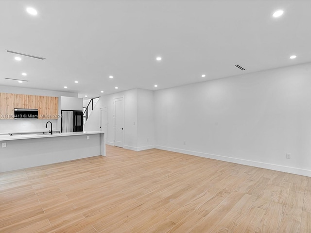 unfurnished living room featuring light wood-style floors, baseboards, and recessed lighting