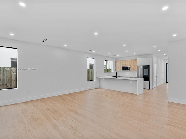 unfurnished living room featuring baseboards, light wood finished floors, and recessed lighting