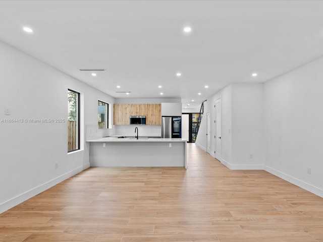 unfurnished living room with baseboards, light wood finished floors, and recessed lighting