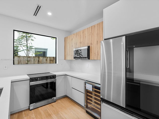 kitchen with visible vents, modern cabinets, wine cooler, appliances with stainless steel finishes, and light countertops