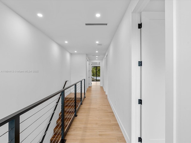 corridor with light wood-type flooring, baseboards, an upstairs landing, and recessed lighting