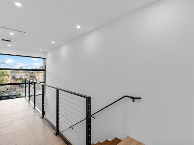 staircase featuring wood finished floors, visible vents, and recessed lighting