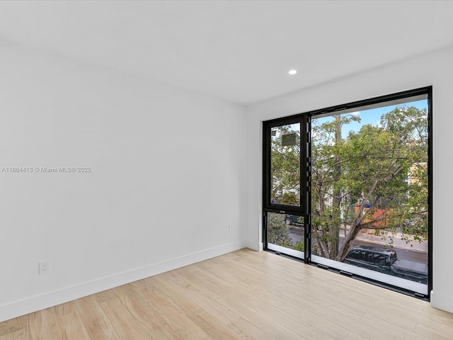 spare room featuring light wood-type flooring, baseboards, and recessed lighting