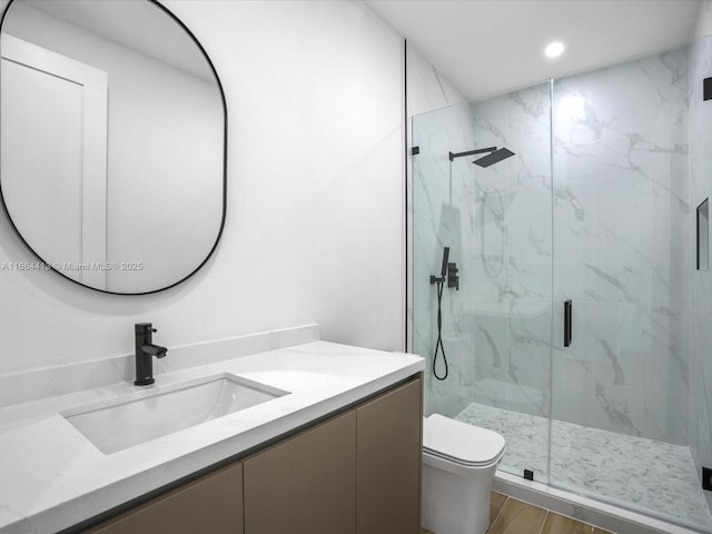 full bath with toilet, a marble finish shower, wood finished floors, and vanity