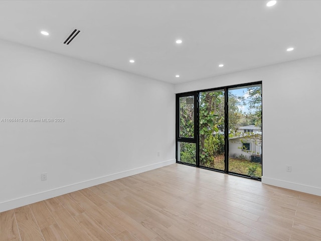 spare room featuring light wood finished floors, visible vents, and recessed lighting