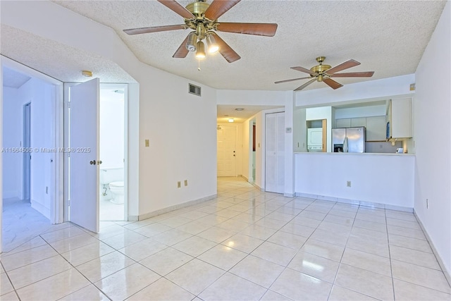 spare room featuring light tile patterned flooring, ceiling fan, and a textured ceiling