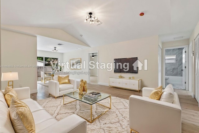 living room featuring hardwood / wood-style floors, a notable chandelier, and vaulted ceiling