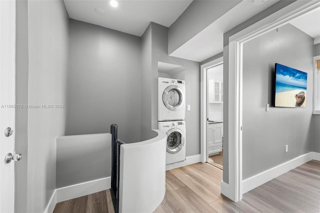 clothes washing area featuring light wood-type flooring and stacked washing maching and dryer