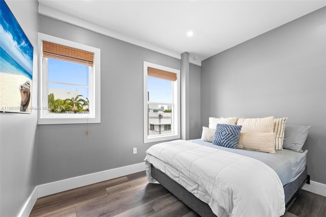 bedroom with dark hardwood / wood-style floors and multiple windows