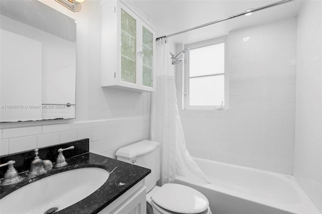 full bathroom with shower / bath combo, vanity, toilet, and tile walls