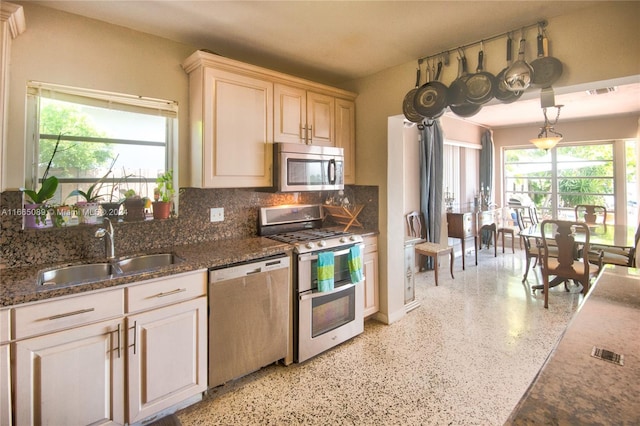 kitchen featuring dark stone counters, tasteful backsplash, sink, stainless steel appliances, and decorative light fixtures