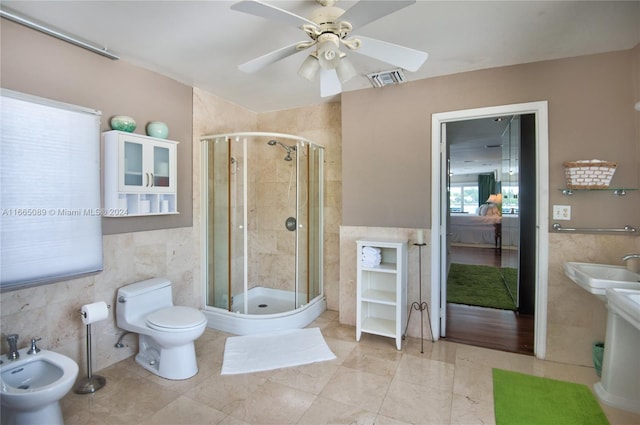 bathroom featuring tile walls, a bidet, a shower with door, and toilet