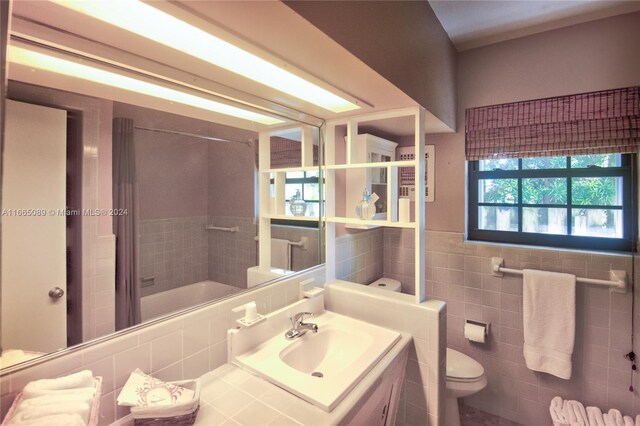 bathroom featuring walk in shower, vanity, tile walls, and toilet