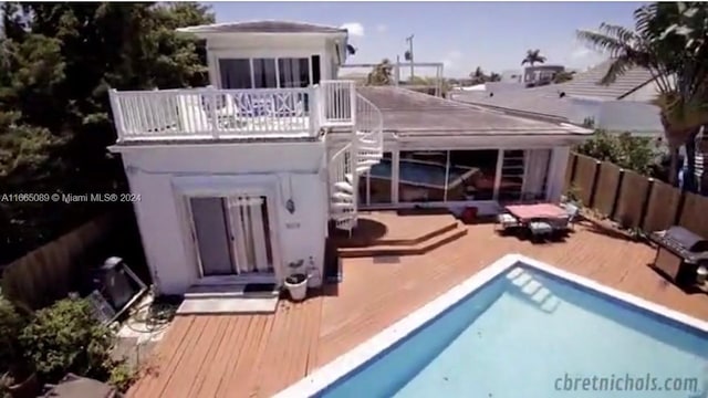 back of house featuring a pool side deck and a balcony