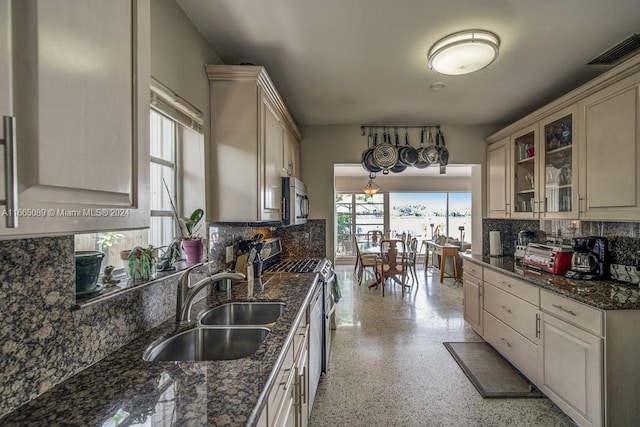 kitchen featuring dark stone counters, stainless steel appliances, a healthy amount of sunlight, and sink