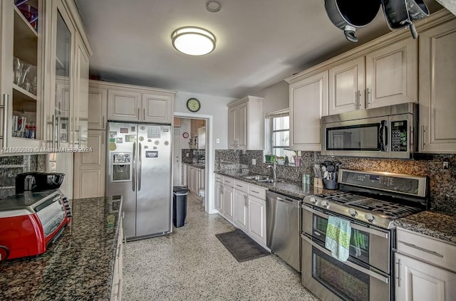 kitchen featuring appliances with stainless steel finishes, sink, and dark stone counters