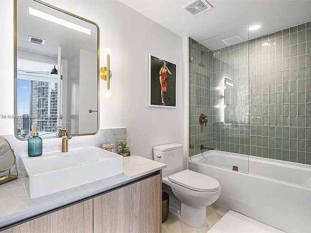 full bathroom with vanity, tile patterned flooring, tiled shower / bath, and toilet