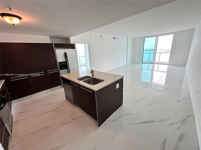 kitchen featuring stainless steel fridge, a kitchen island with sink, sink, and black dishwasher